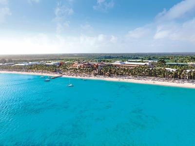 Uitgestrekt strand met turquoise water en hotelcomplex op de achtergrond onder een blauwe lucht.