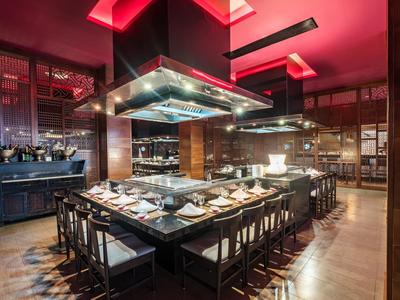 Modern restaurant met rode plafondlampen en elegant gedekte tafels.