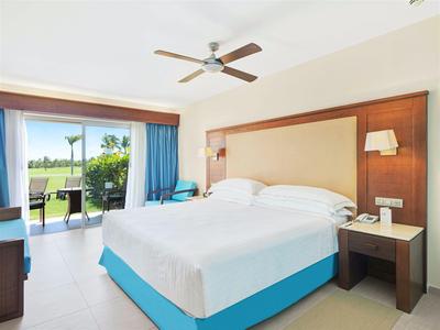 Lichte hotelkamer met groot bed en terras met uitzicht op groen.