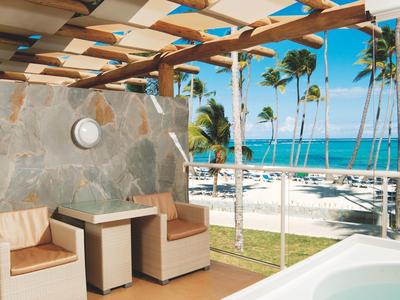 Hotelkamer met twee bedden, bureau, tv en terras met uitzicht op groene tuin