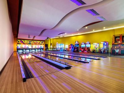 Helle Bowlingbahn mit mehreren Bahnen und Spielautomaten an der Wand.