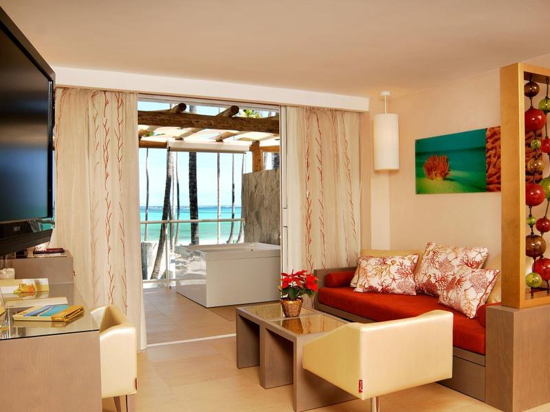 Strand met veel palmbomen, ligstoelen en helderblauwe zee op de achtergrond.