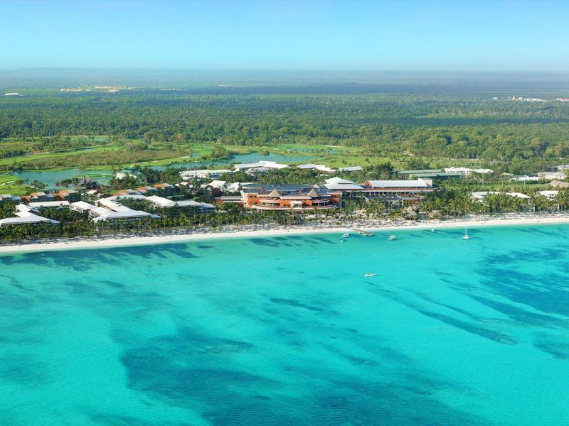 Luchtfoto van een resort aan een wit zandstrand met helder turquoise water.