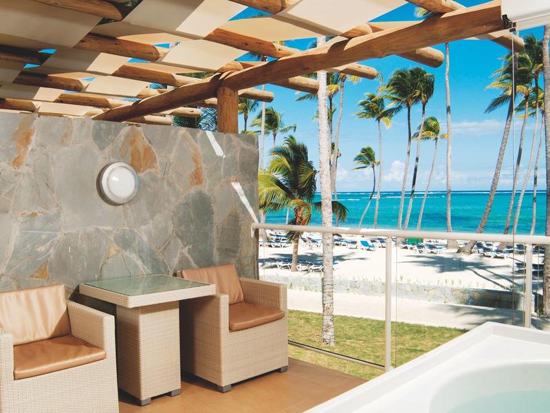 Hotelkamer met twee bedden, bureau, tv en terras met uitzicht op groene tuin