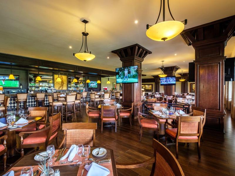 Een stijlvol restaurant met warme houten inrichting, gedekte tafels en zachte verlichting.