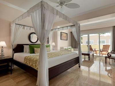 Elegantes Hotelzimmer mit Himmelbett, Sitzbereich und Blick auf die Terrasse