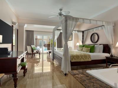 Helles Hotelzimmer mit Himmelbett, Sitzecke und Badewanne im Vordergrund.