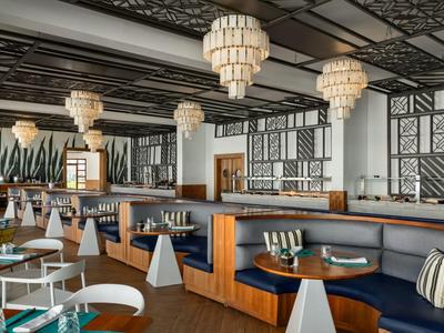 Modernes Restaurant mit blauen Sitzbänken, weißen Tischen und großen Kronleuchtern in elegantem Ambiente.