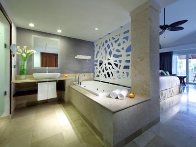 Modernes Badezimmer mit großer Badewanne, Waschbecken, Teppich und offenem Zugang zum Schlafzimmer.