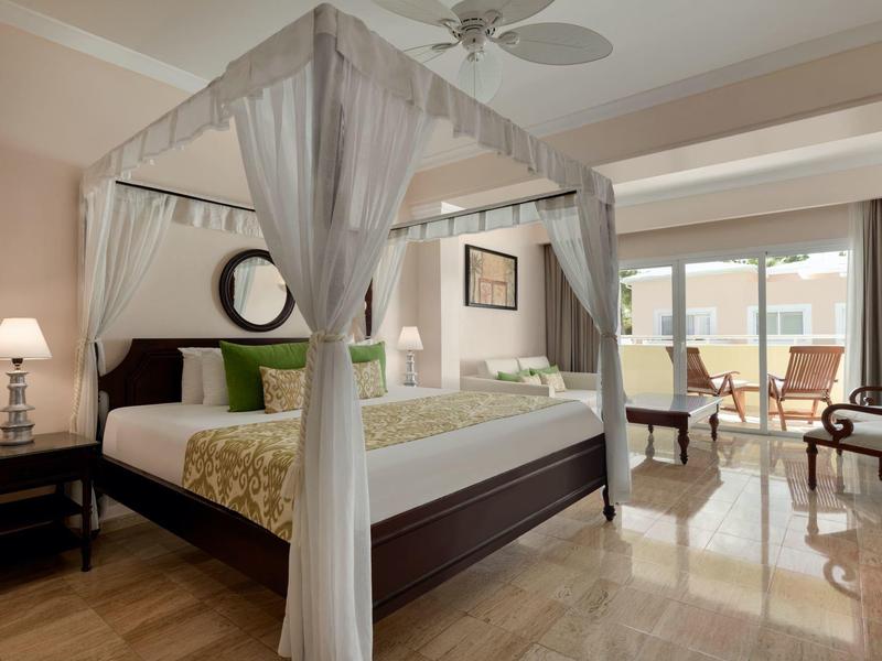 Elegantes Hotelzimmer mit Himmelbett, Sitzbereich und Blick auf die Terrasse