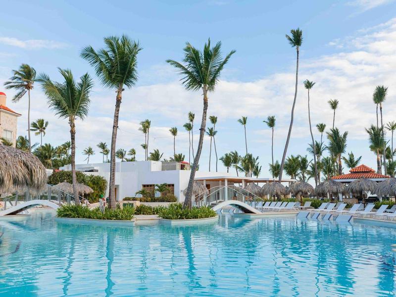 Schwimmbecken mit Liegestühlen und Palmen unter klarem Himmel in einem Hotelresort