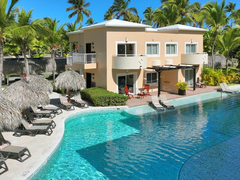 Moderner zweistöckiger Hotelkomplex mit großem Pool und Palmen in tropischer Umgebung