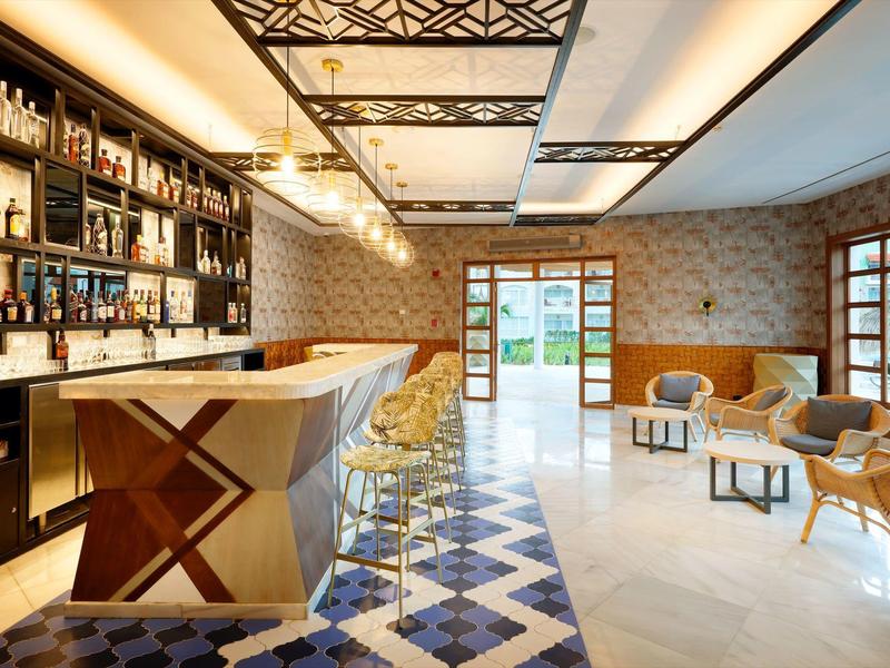 Moderner Hotelbarbereich mit stilvollem Tresen, Sitzgelegenheiten und großem Fenster mit Blick nach draußen.