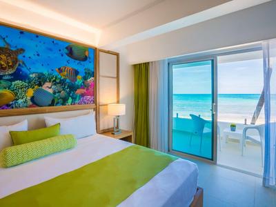 Moderne hotelkamer met zeezicht en kleurrijk onderwaterbeeld boven het bed.