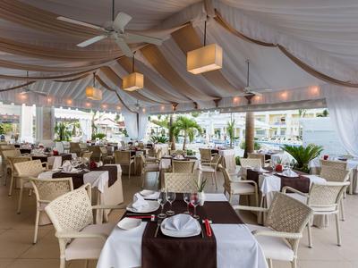 Elegant covered restaurant with white tables and brown runners in a hotel.
