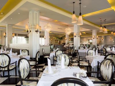 Elegant dining room with white-covered tables and classic chairs in light colors.