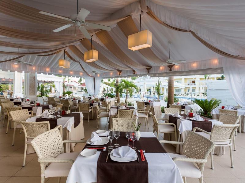 Elegant covered restaurant with white tables and brown runners in a hotel.