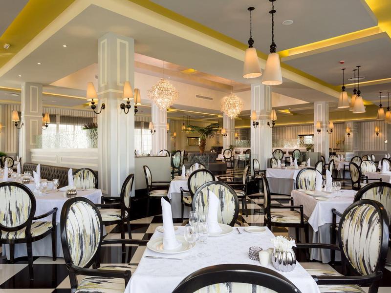 Elegant dining room with white-covered tables and classic chairs in light colors.