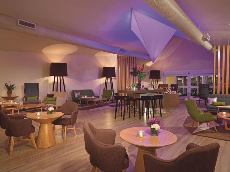 Gemütlicher Lounge-Bereich mit Sitzgruppen, Tischen und gedimmtem Licht in einem Hotel.