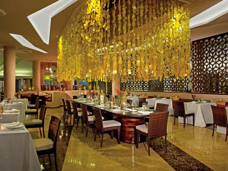 Elegantes Restaurant mit modernen Holzmöbeln und kunstvoller Deckenbeleuchtung.