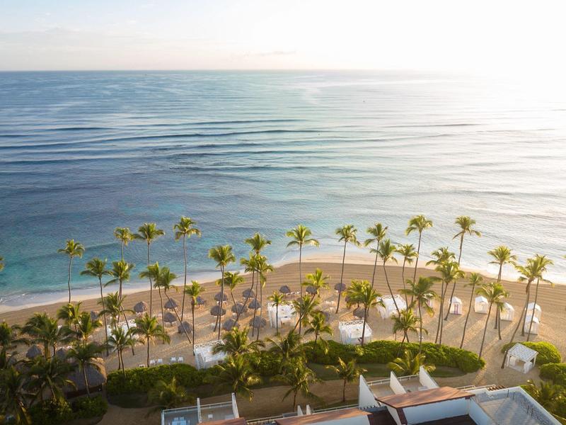Strand mit Palmen und ruhigem Meer bei Sonnenuntergang, Blick von oben auf Hotelanlage