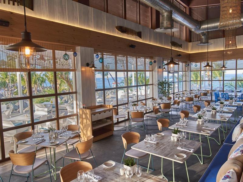 Restaurante moderno con grandes ventanas y vista al mar en un hotel.