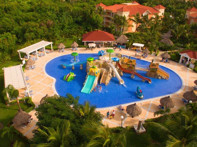 Piscina redonda para niños con toboganes y juegos en un hotel tropical.