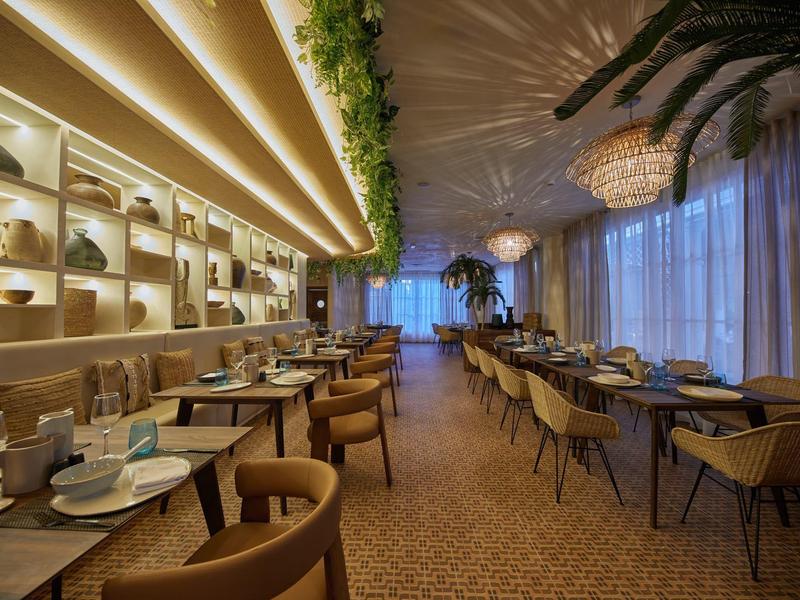 Modernes Restaurant mit elegantem Beleuchtungskonzept, Pflanzen und gemütlichen Sitzgruppen.