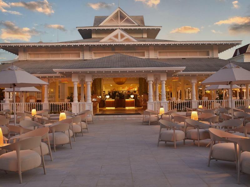 Großes offenes Restaurant mit warmen Lichtern, vielen Tischen und Stühlen unter hellem Himmel.