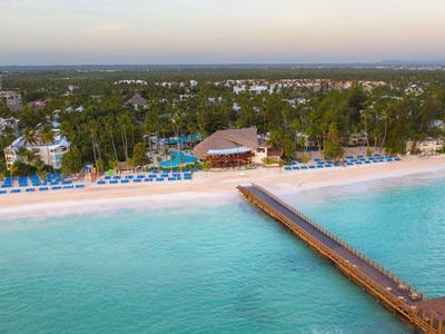 Resort sulla spiaggia con molo di legno e ombrelloni blu sul mare turchese.