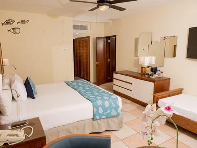 Camera d'hotel moderna con due letti, ventilatore da soffitto e comò con specchi.