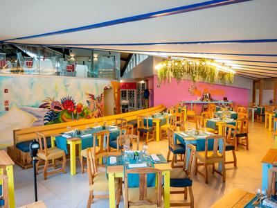 Ristorante luminoso con sedie colorate e decorazioni moderne sotto una tenda blu.