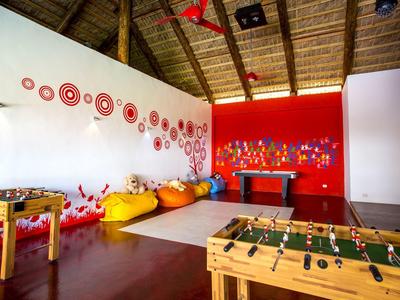 Sala ricreativa con tavoli da calcio balilla, pouf colorati e decorazioni murali rosse vivaci.