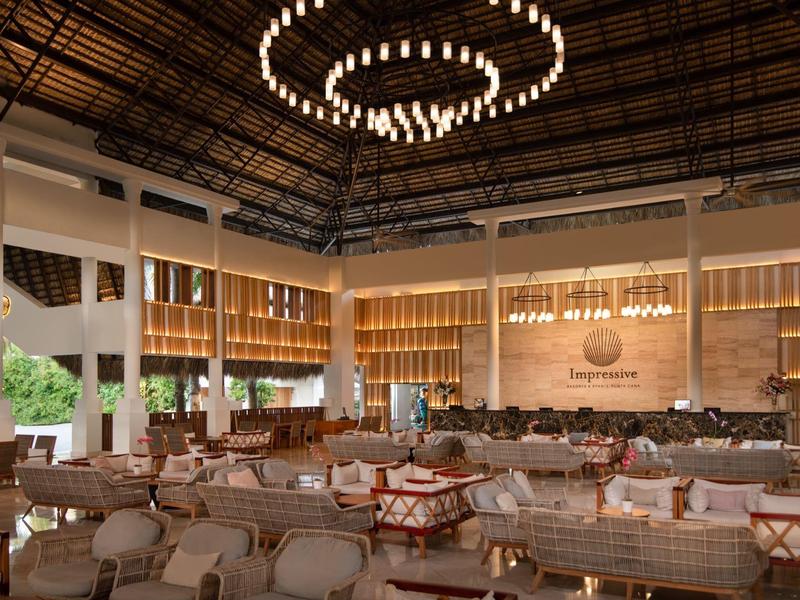 Ampia hall dell'hotel con comode aree salotto e un moderno lampadario.