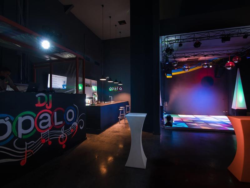 Interno di un bar DJ elegante con postazione DJ illuminata e pista da ballo.