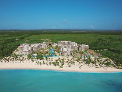 Luxe resort aan een wit zandstrand met palmbomen en turquoise water.