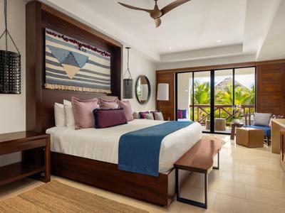 Moderne hotelkamer met tweepersoonsbed, balkon en tropisch uitzicht.