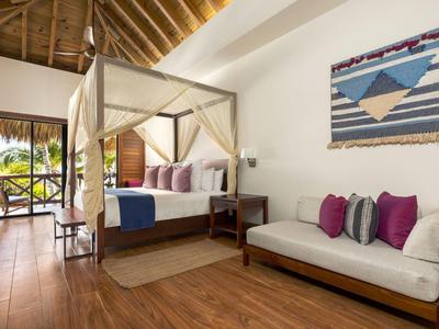 Kamer met houten vloer, hemelbed en bank naast een wandtapijt in een hotel.