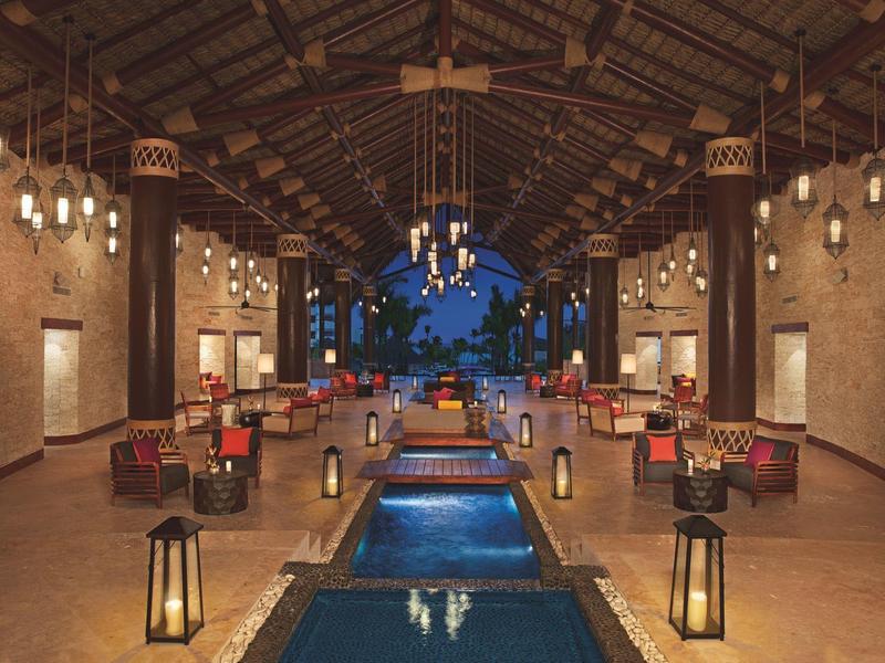 Overdekte eetruimte met open einde en centraal waterornament, omringd door tafels en lampen.