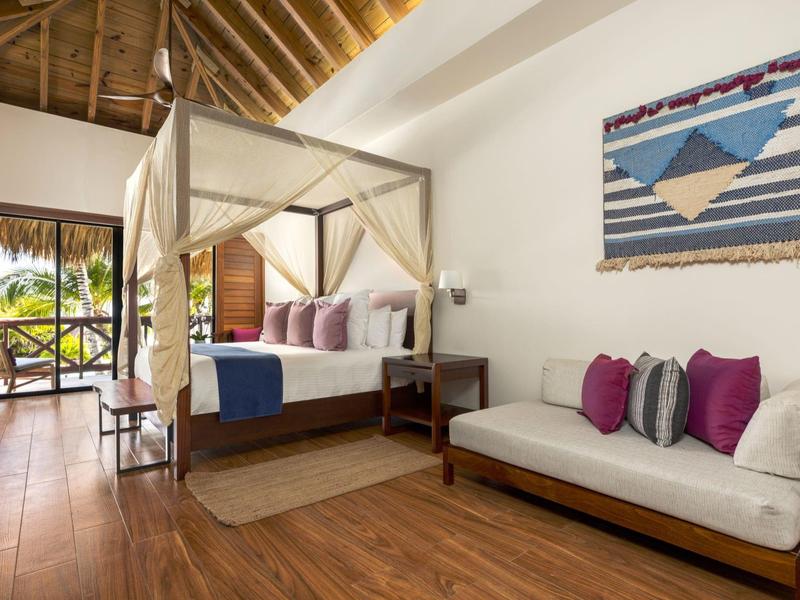 Kamer met houten vloer, hemelbed en bank naast een wandtapijt in een hotel.