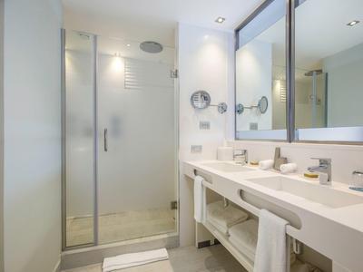 Modern bright hotel bathroom with toilet, shower, and large mirror.