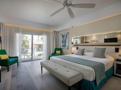 Jasny pokój hotelowy z dużym łóżkiem, miejscem do siedzenia i balkonem z widokiem