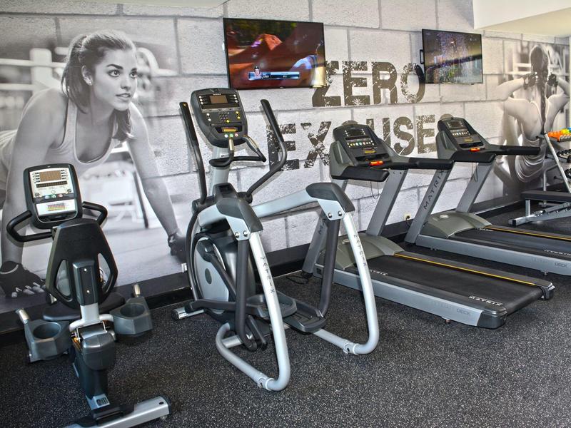 Modern gym with exercise machines in front of a wall featuring a large fitness mural.