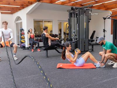 Various people exercise in a well-equipped gym with machines and mats.