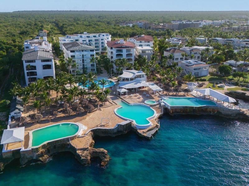 Letecký pohled na přímořské letovisko s několika bazény a čistou mořskou vodou