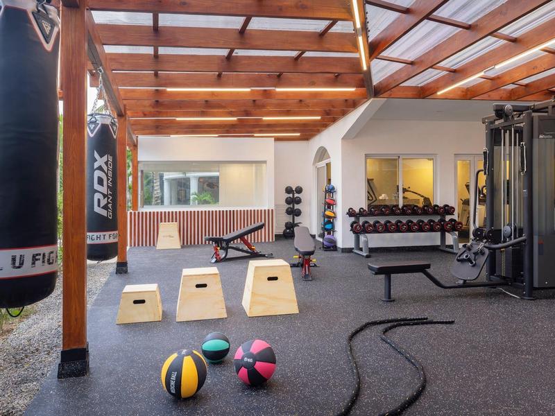 Moderní fitness prostor s boxovacím pytlem, medicinbaly, závažími a fitness vybavením.