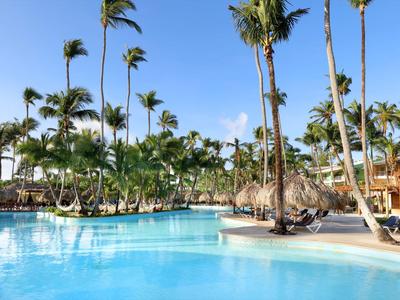 Large swimming pool with palm trees and blue sky at a tropical hotel resort.