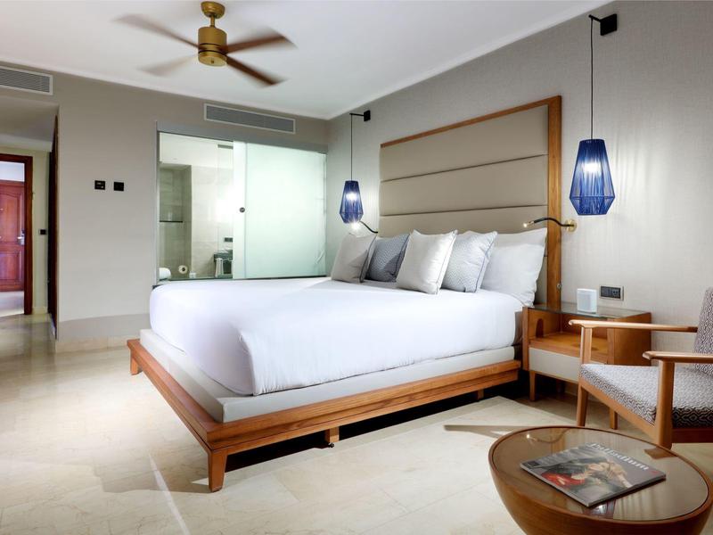 Moderne hotelkamer met groot bed, nachtkastjes en zithoek.