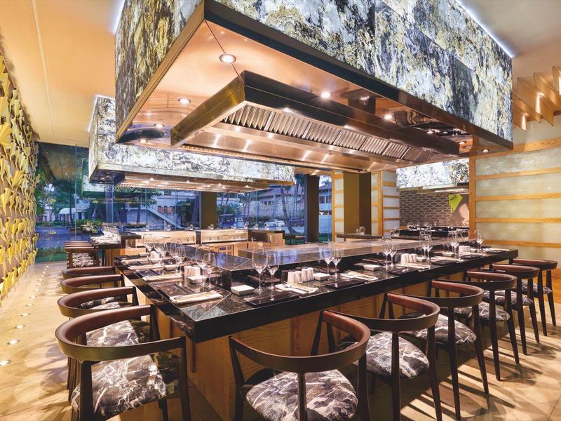 Modern restaurant met houten meubels en een grote centrale open haard.