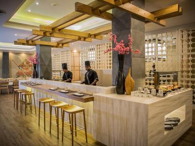 Nowoczesny bar hotelowy z jasnym marmurem, drewnianymi stołkami i subtelnym oświetleniem.